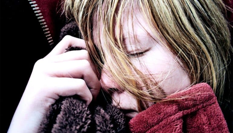 A woman sleeps holding onto a blanket