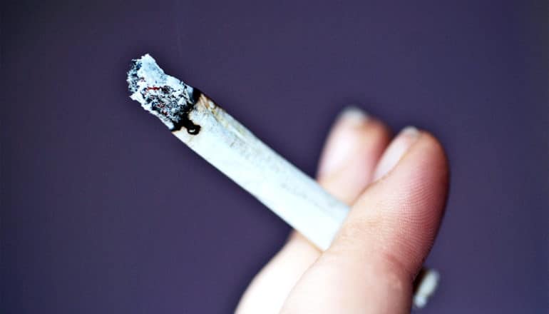 A woman holds a joint between two fingers