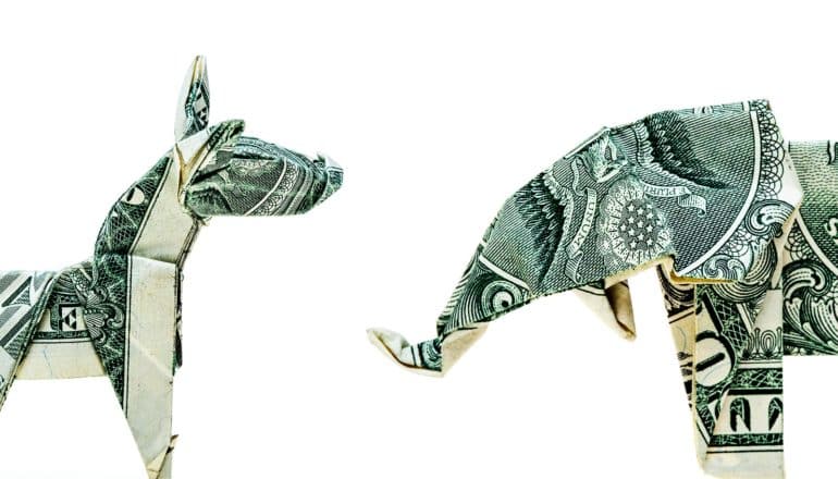 Dollar bills folded into a donkey and an elephant face off on a white background