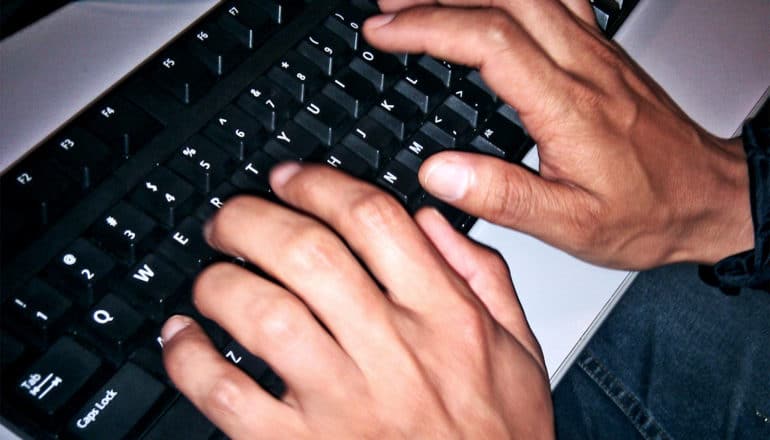 A person types on a black keyboard