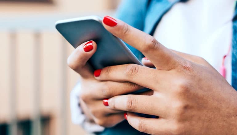 A young woman holds her phone and looks to be texting