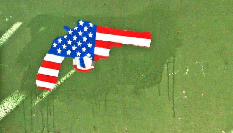 An American flag in the shape of a gun painted on a green wall