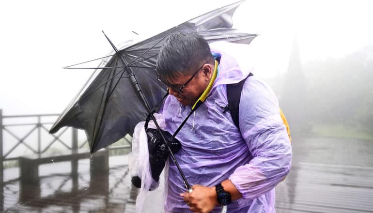 A man holds onto a broken umbrella in a wild storm