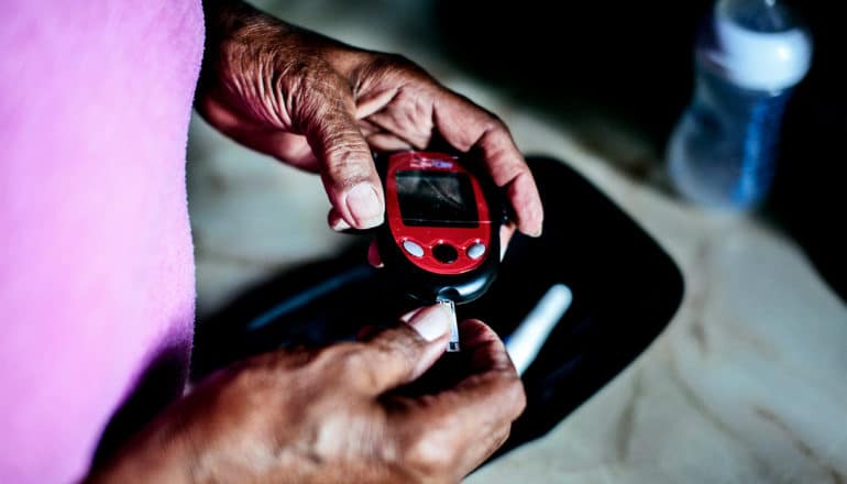 An older woman holds a blood sugar testing device