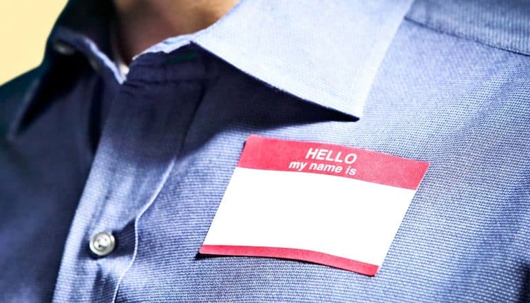 A person wearing a blue collared shirt has a blank name tag on his chest