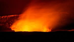 A volcano glows orange as red-tinted smoke drifts out