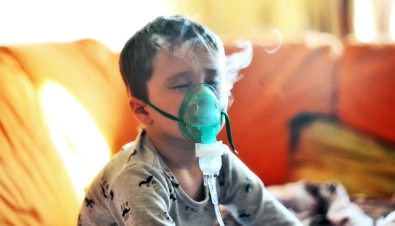 A boy breathes through a nebulizer