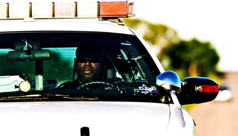 A police officer sits in a squad car