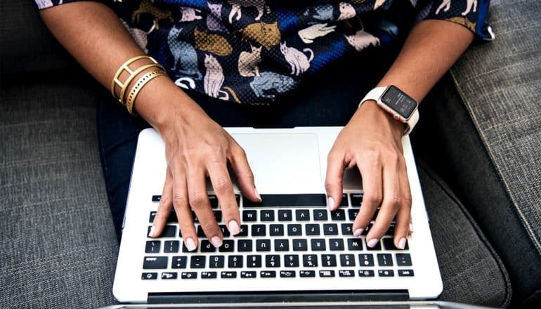 A woman types on a laptop