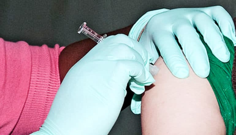 A health worker injects a patient with a vaccine