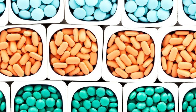 A series of white containers hold colorful pills