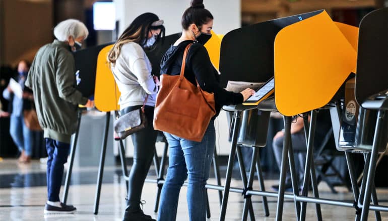 Voters cast ballots wearing face masks