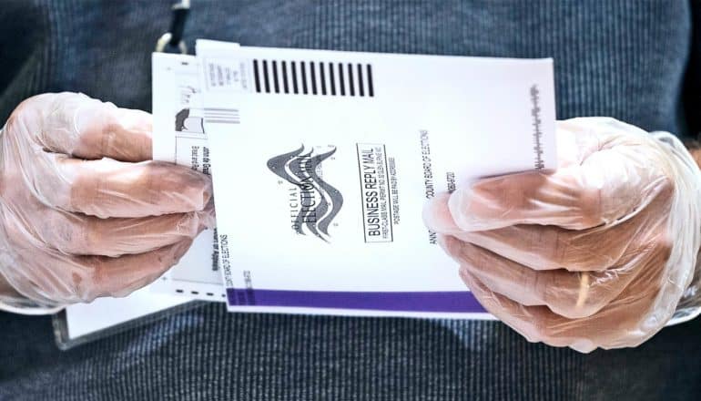 An election worker opens a mailed-in ballot