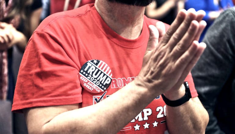 A man holds his hands together in prayer at a Donald Trump rally