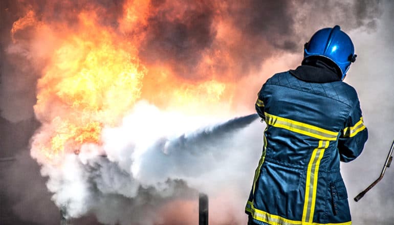 A firefighter sprays foam at a test fire