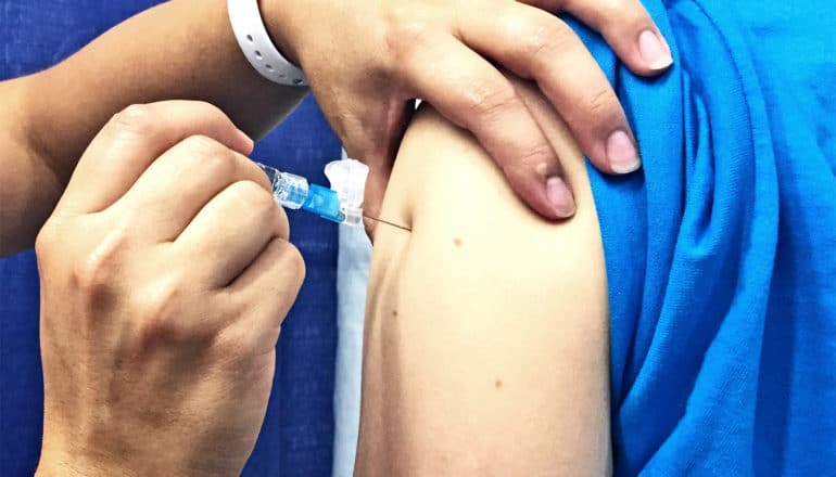 A person in a blue shirt gets a flu shot