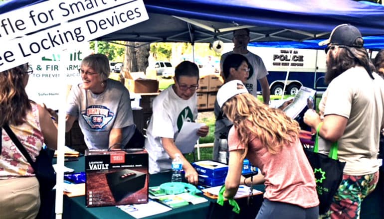 Volunteers speak to people at a gun show from a small tent