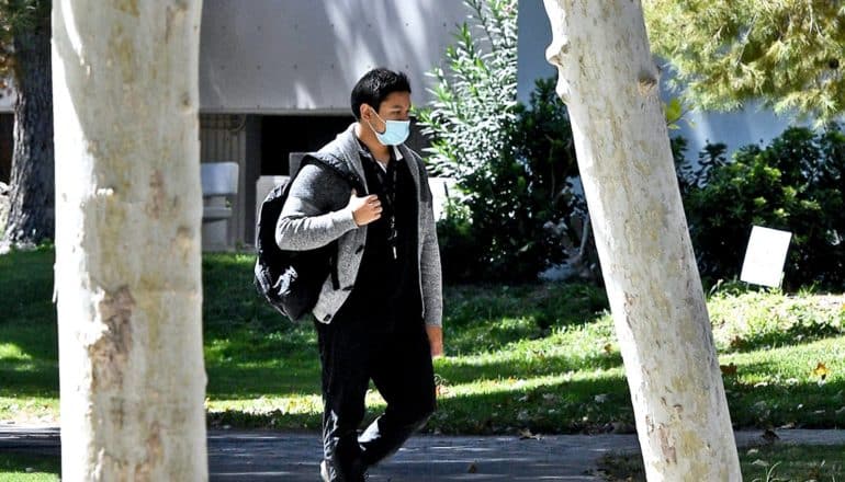 A college student walks to class wearing a face mask