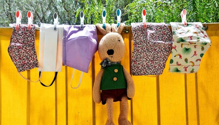 Face masks and a child's stuffed rabbit hang on a clothes line