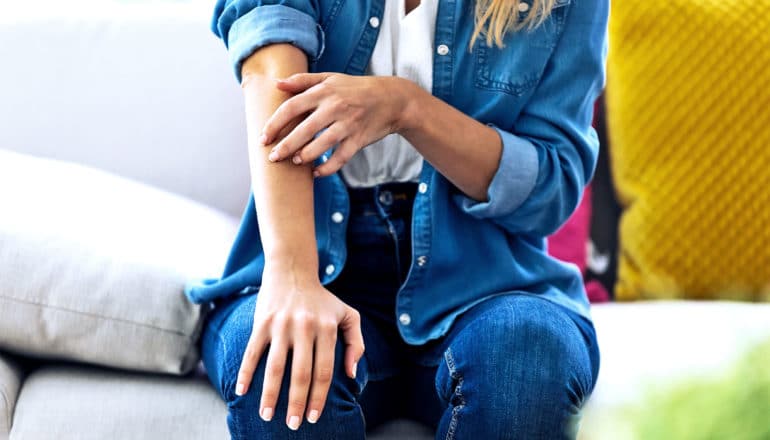 A woman touches the skin on her arm