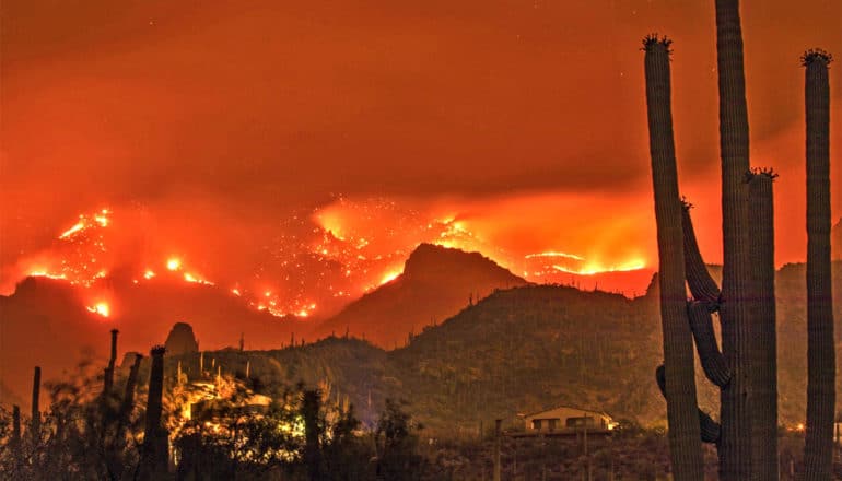 Wildfire burns on the far side of a mountain range