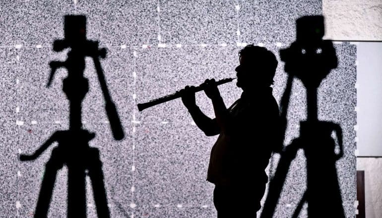 A musician plays an oboe in silhouette
