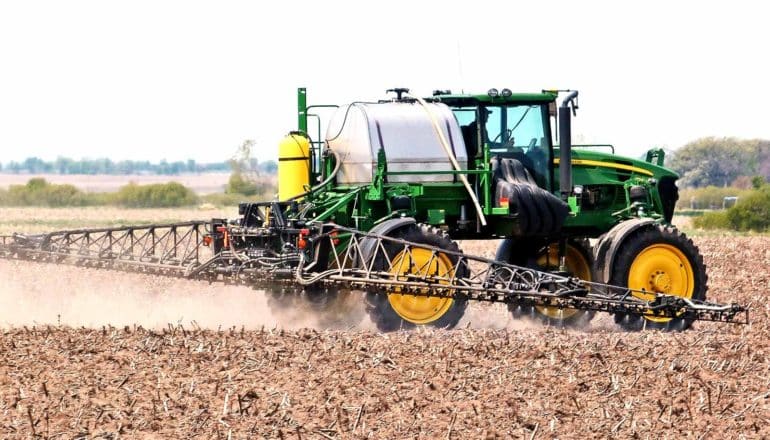 A tractor sprays fertilizer and pesticide on a field