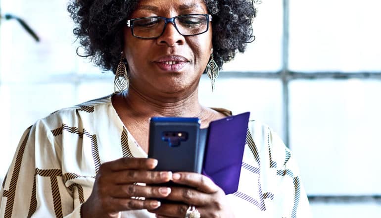 A woman looks down at her phone with suspicion