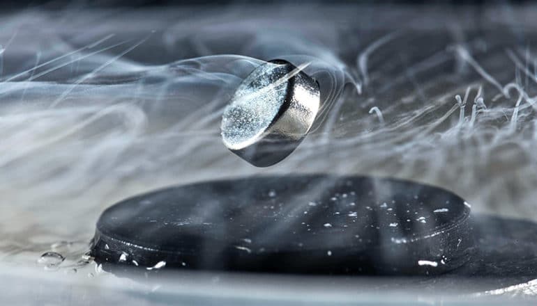 A magnet levitates above a black superconductor