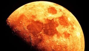 The moon looks bright orange against a black background