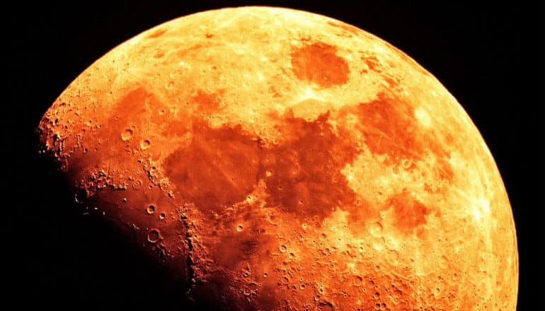 The moon looks bright orange against a black background