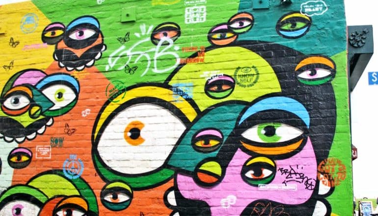 Street art on a brick wall showing many eyes in different colors and sizes