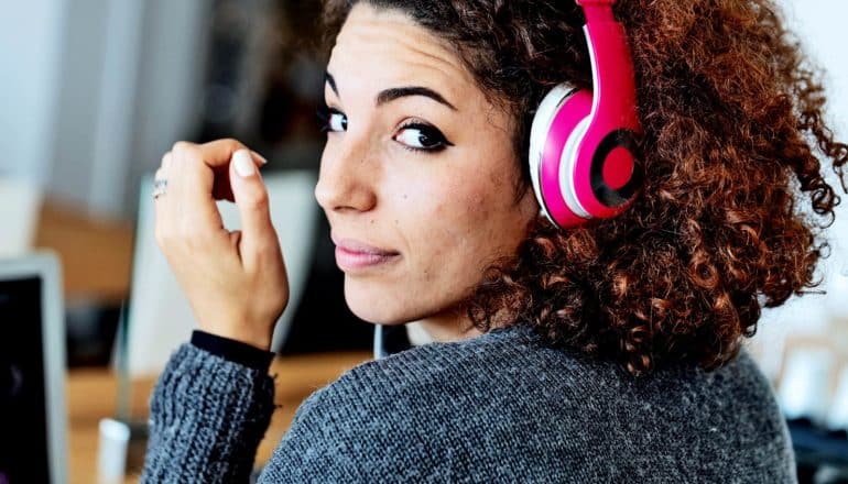 A woman wearing headphones looks over her shoulder while working