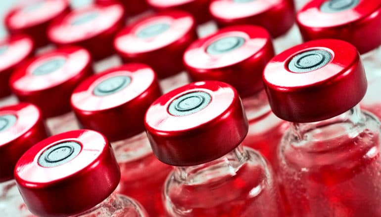 vaccine vials with red tops sit in rows