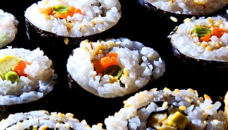 Rows of sushi rolls filled with sticky white rice and vegetables