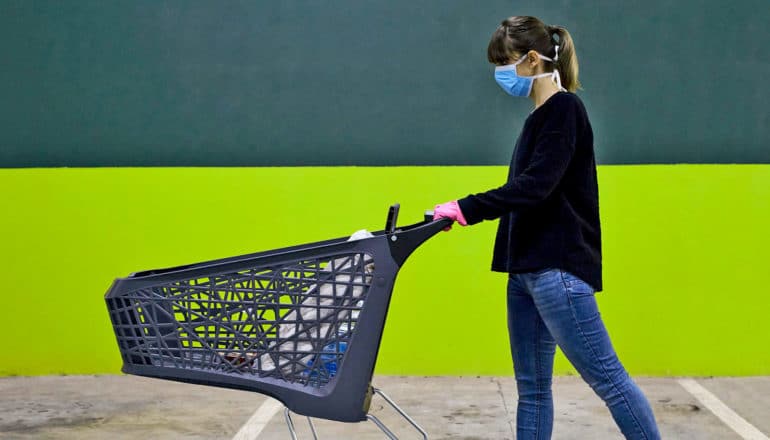 person in mask pushes shopping cart