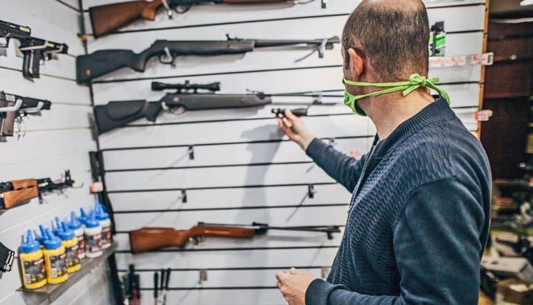 person in mask looks at gun display