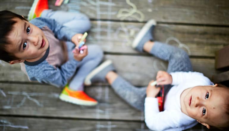 preschooler and toddler on wood porch with chalk