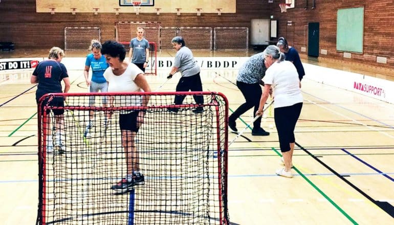 The women in the study play floorball in a gymnasium using what look like field hockey sticks