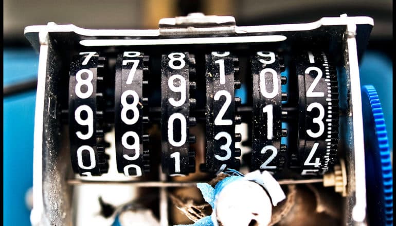 A broken date-making machine has several side-by-side black dials covered in numbers 0-9