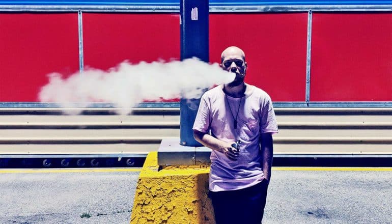 A man is vaping on a train platform