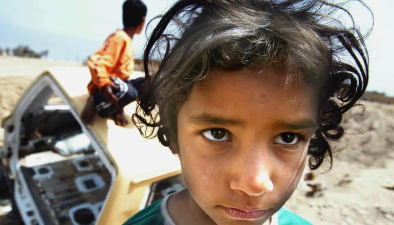 girl looks serious and devastated in front of destroyed vehicle