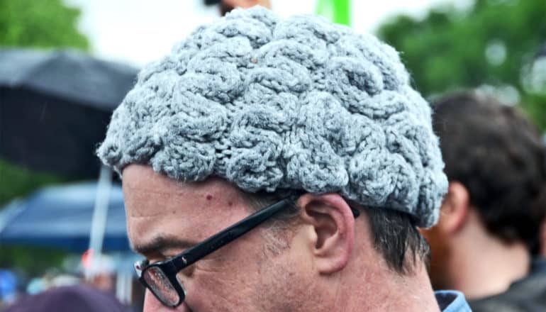 A man wears a gray knitted cap that looks like a brain