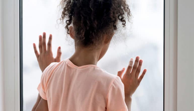 child looks lonely at glass door