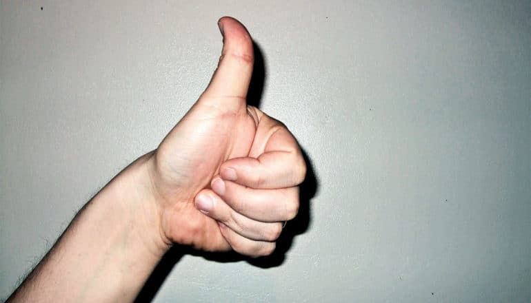 A person makes a "thumbs up" sign