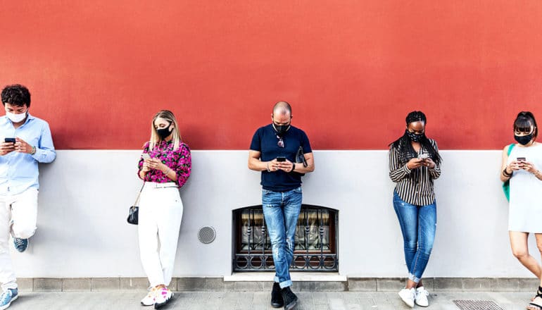 A row of people leaning against a wall