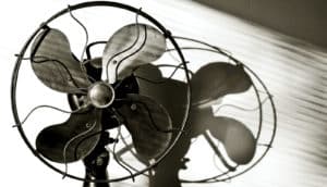 An antique electric fan against a white wall