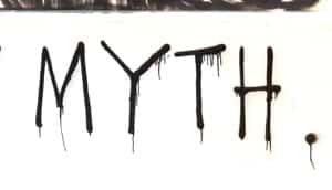 The word "myth" is spray-painted in black on a wall