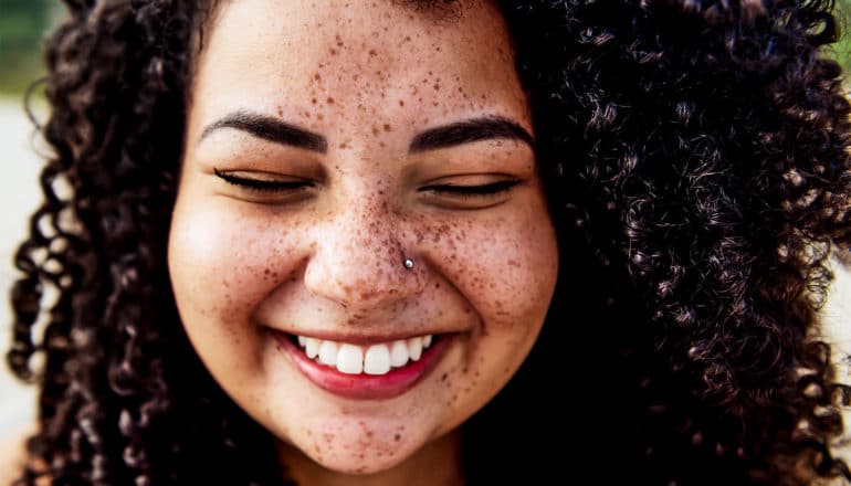 A woman smiles sincerely while closing her eyes