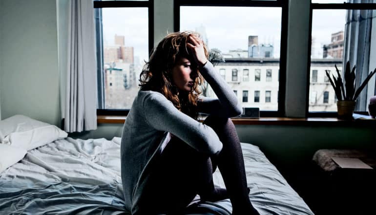 A woman sits alone on her bed